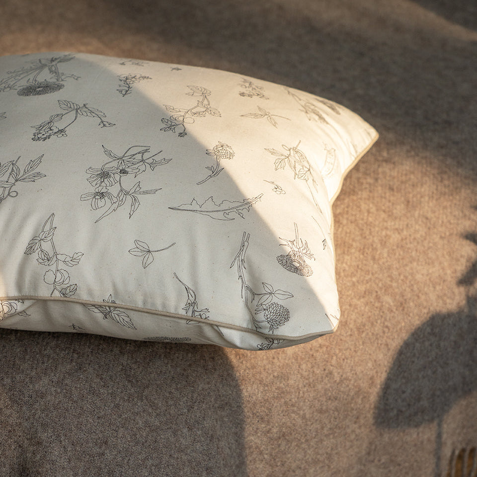 floral cushion with piping on a beige throw