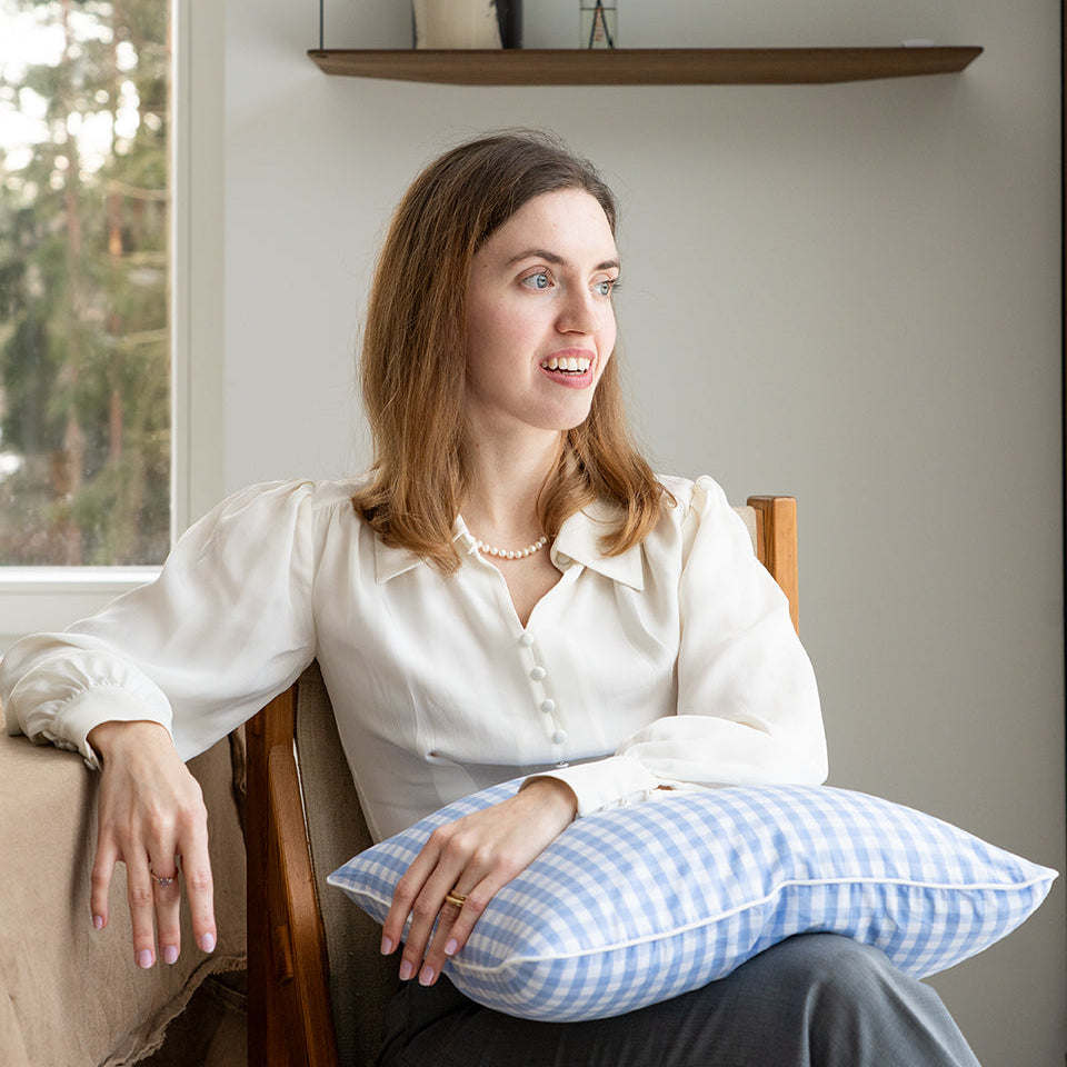 woman sitting on a chair holding a blue gingham cushion