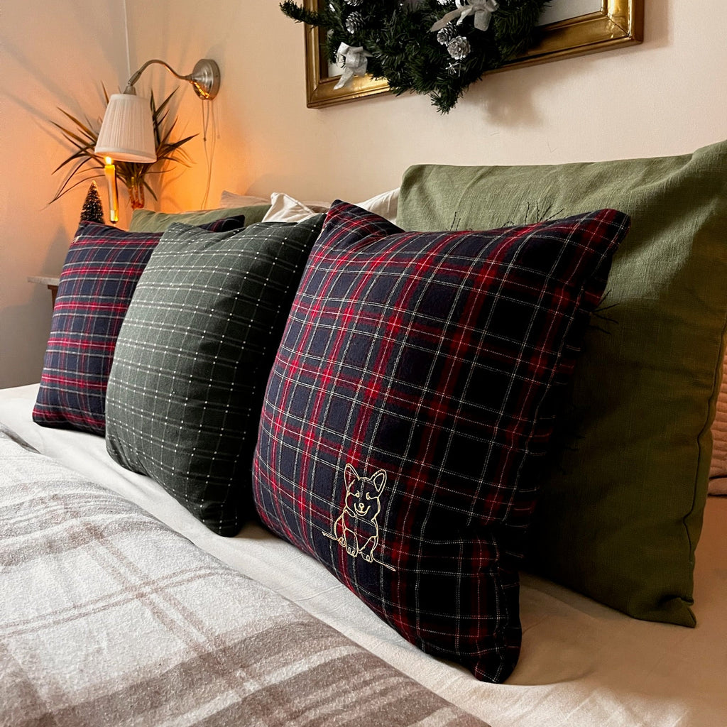 Decorative pillows on a bed with a Christmas wreath on the wall.