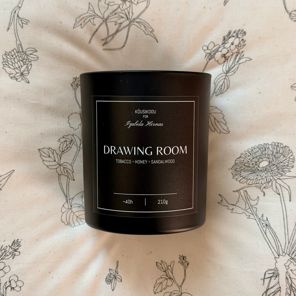 Black candle container labeled 'Drawing Room' on a floral-patterned background