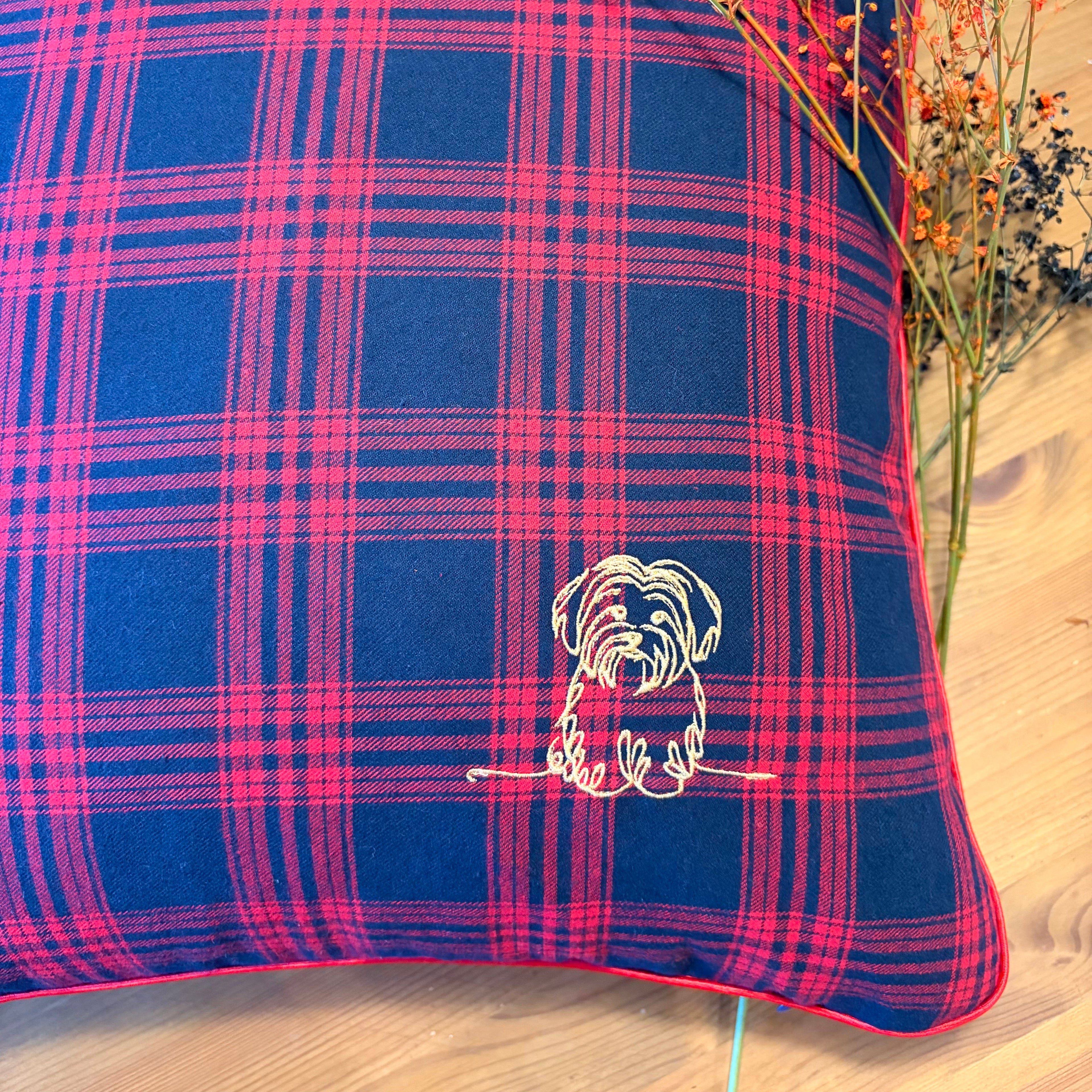 Plaid pillow with a embroidered design on a wooden surface