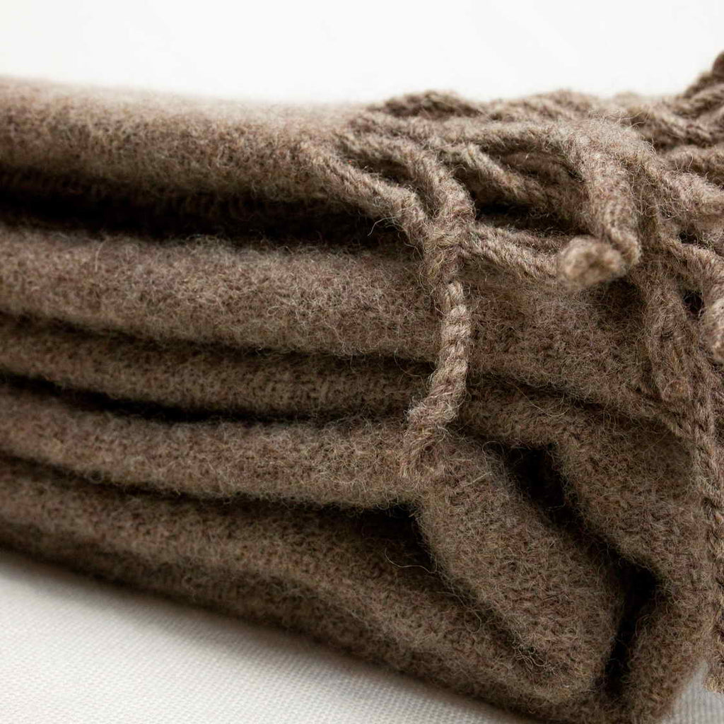 Stack of brown textured towels with tassels on a white background