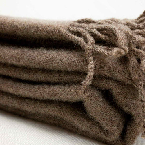 Stack of brown textured towels with tassels on a white background