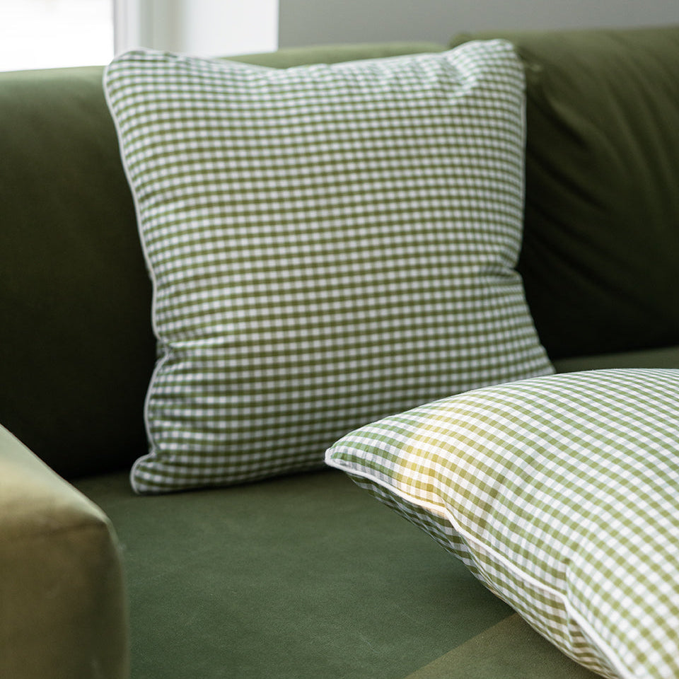 two green gingham cushions on a green sofa